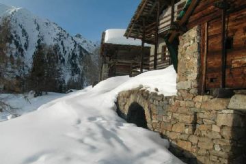 Case Walser sotto la neve, nel Vallone di San Grato, a Ruassi. Da rilevare un antico forno posizionato sotto l'arco in pietra.<br>